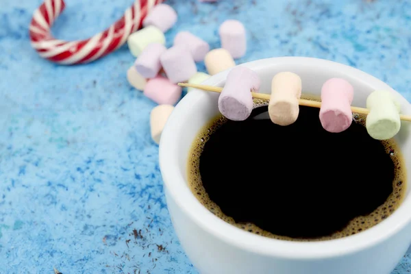 Xícara branca de café e marshmallows na mesa. vista vertical. lugar para texto. Fundo azul abstrato . — Fotografia de Stock