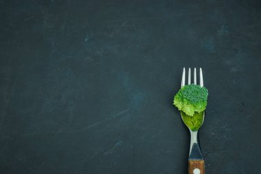 Taze yeşil Brokoli lahana bir çatalı yatıyor. Şablon karanlık bir arka plan üzerinde sağlıklı gıda /. Alanı yukarıdan kopyalayın. Vejetaryen yiyecekler. yukarıdan görüntülemek.