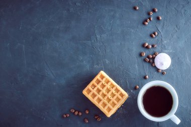 Homemade breakfast, stone black table. Viennese waffles, a cup of coffee, scattered coffee beans, top view, copy space clipart