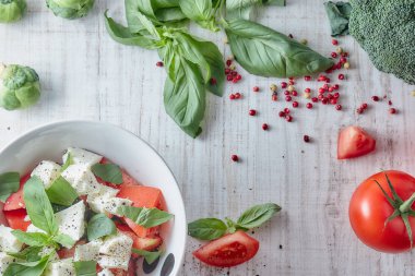 Ahşap arka plan, beyaz peynir ve fesleğen taze sebze ile Yunan salatası. Aşk için sağlıklı çiğ gıda kavramı.