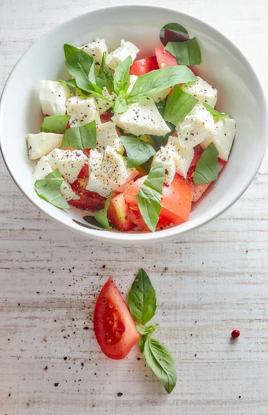 Ahşap arka plan, beyaz peynir ve fesleğen taze sebze ile Yunan salatası. Aşk için sağlıklı çiğ gıda kavramı.