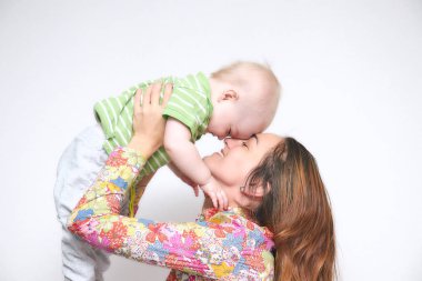 esmer genç anne, küçük bir bebek çocuk onu tutan kız eğlenirken silah. Aile ortamı ile gülümsüyor. mutlu aile gülümsüyor.