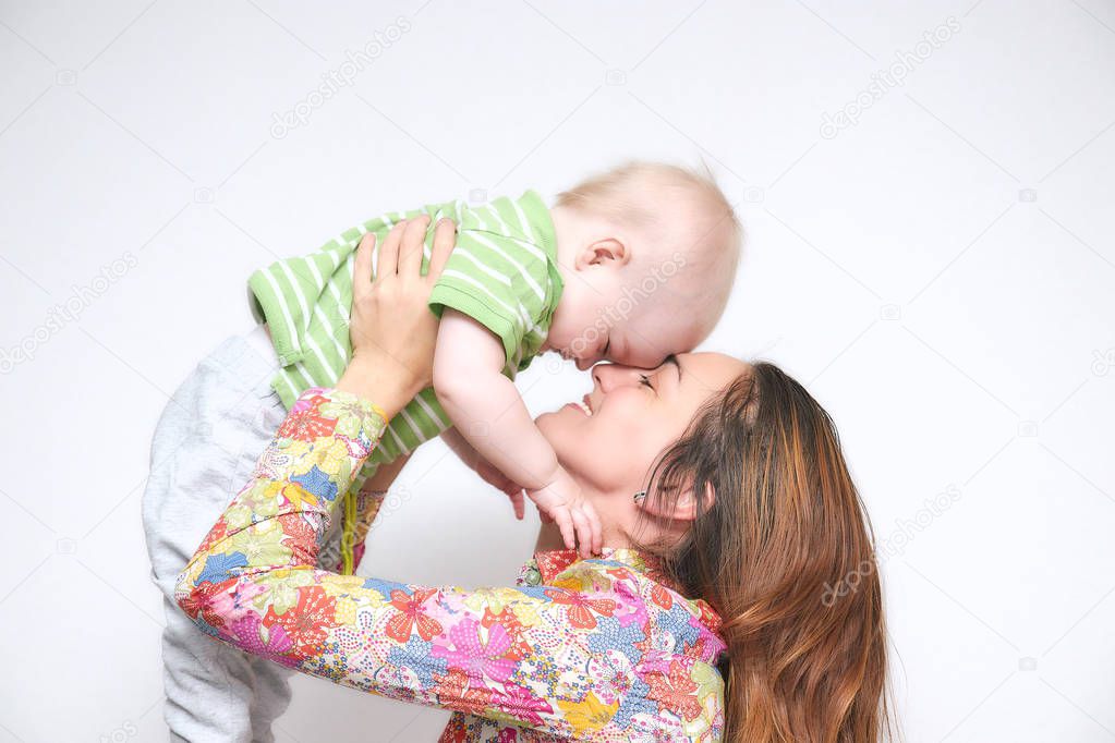 brunette young mom, girl holding a little baby boy in her arms frolicking. family atmosphere with smiles. happy family smiles.