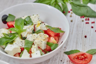 Ahşap arka plan, beyaz peynir ve fesleğen taze sebze ile Yunan salatası. Aşk için sağlıklı çiğ gıda kavramı.