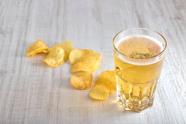 a glass of cold, light beer with chips scattered on the table. copy space. the view from the top. minimalism