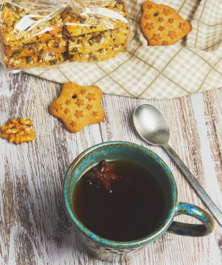 Seramik Kupa çay siyah beyaz, eski, eski püskü ahşap bir masa üzerinde fındıklı kurabiye bir avuç. sabah kahvaltı çerezler ile kompozisyon.