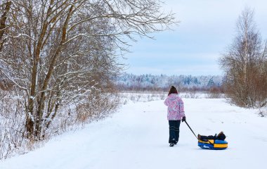a young mother pushing a small child in winter . clipart