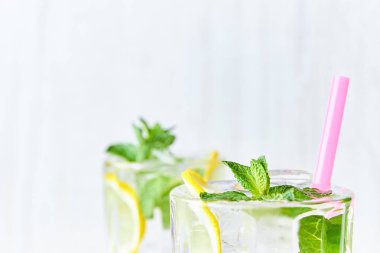Buz, limon dilimleri ve nane hafif ahşap arka plan üzerinde saman ile bir bardak limonata. kopya alanı. Yaz, içki yenileniyor.