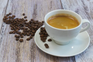 Bir fincan güzel kokulu siyah kahve ve kahve çekirdekleri eski bir ahşap masa yakın çekim üzerinde bir avuç. Sabahları içecek.