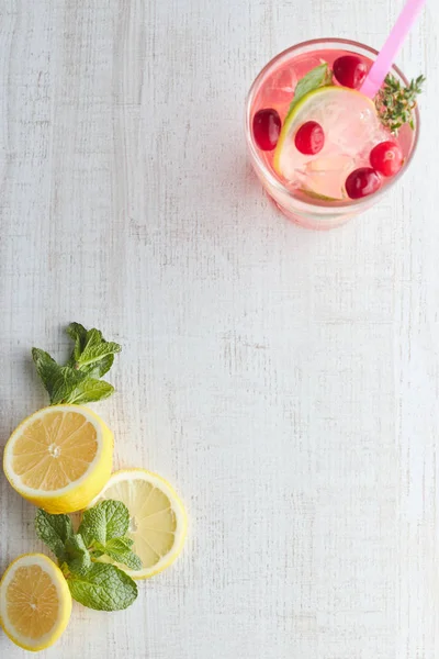 Освежающий летний напиток с ягодами и лимоном на светлом деревянном столе. Концепция летних напитков со льдом. стакан с летним коктейлем с соломой . — стоковое фото