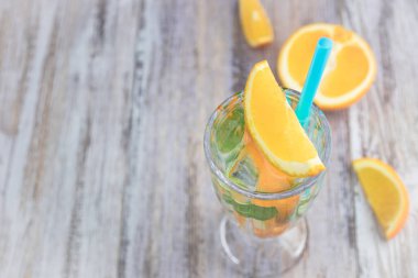 Narenciye ferahlatıcı ahşap bir masa üzerinde bir cam kadeh içki. Yaz ferahlatıcı kokteyl. Sağlıklı gıda, içecekler. turuncu ve nane buzlu su. Uzay kopyalayın. Yatay görünüm.