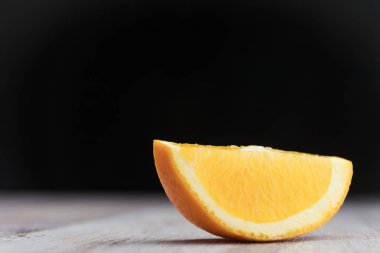 Portakal dilim ahşap masa üzerinde. Turuncu yakın çekim kesim içinde. Siyah arka plan. Kopya alanı