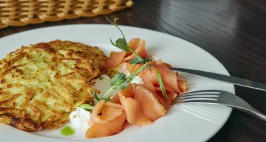 ahşap bir masa üzerine dereotu ve patates pancakes ile Marine somon çanak. taze salamura alabalık. bir tabak çanak. Rus gıda. Yatay görünüm.