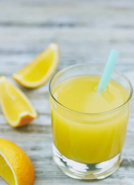 Szklany świeży sok pomarańczowy i owoce pomarańczowe na drewnianym stole. widoku pionowym. orzeźwiający napój cytrusowy. — Zdjęcie stockowe