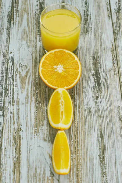 Ein Glas frischen Orangensaft und Orangenfrüchte auf einem Holztisch. vertikale Ansicht aus nächster Nähe. Erfrischendes Zitrusgetränk. — Stockfoto