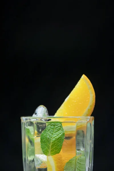 Portakal ve nane ile sağlıklı Detoks su. Ferahlatıcı bir yaz içeceği siyah arka plan üzerine kapatın. narenciye kokteyl.