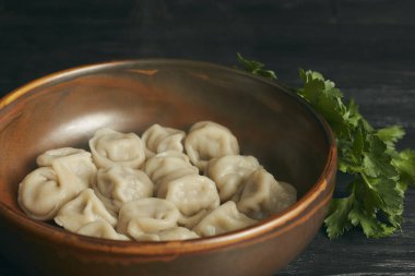 Siyah ahşap masada tereyağı ve yeşillikler ile Pelmeni. Hamur ve kıyma Rus geleneksel yemek. Fotoğraf kapatın. çanak yatay görünümü.