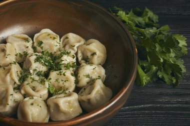 Siyah ahşap masada tereyağı ve yeşillikler ile Pelmeni. Hamur ve kıyma Rus geleneksel yemek. Fotoğraf kapatın. çanak yatay görünümü.