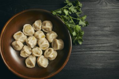 Siyah ahşap masada tereyağı ve yeşillikler ile Pelmeni. Hamur ve kıyma Rus geleneksel yemek. Fotoğraf kapatın. çanak yatay görünüm. Kopyalama alanı.