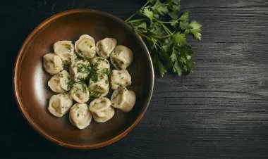 Siyah ahşap masada tereyağı ve yeşillikler ile Pelmeni. Hamur ve kıyma Rus geleneksel yemek. Fotoğraf kapatın. çanak yatay görünüm. alanı kopyalayın. Yukarıdan görünüm