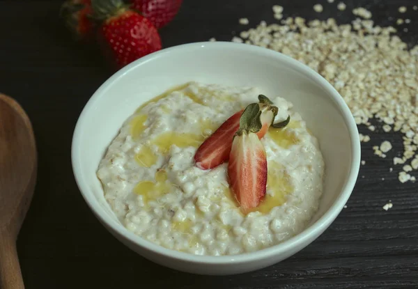 Здоровый и вкусный завтрак. Овсянка с клубникой на черном деревянном столе. горизонтальный вид. rustic — стоковое фото