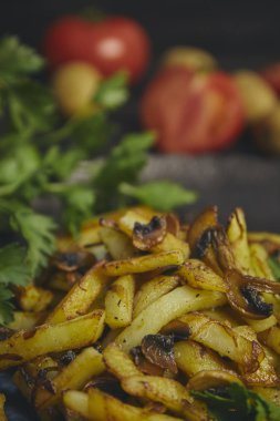 Taze soğan ve mantar yakın çekim bir tabak kızarmış patates pişmiş. abanoz tablo. yemeğin dikey görünüm.