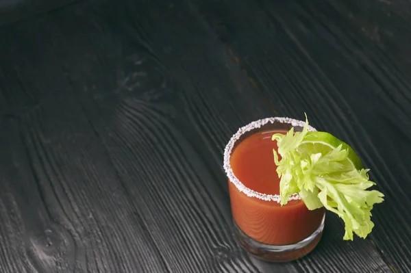 Krwawa mary cockcocktail Bloody Mary z limonką i seler, sól i przekąski w szklance na czarny drewniany stół. poziomy widok cocktail.tail — Zdjęcie stockowe