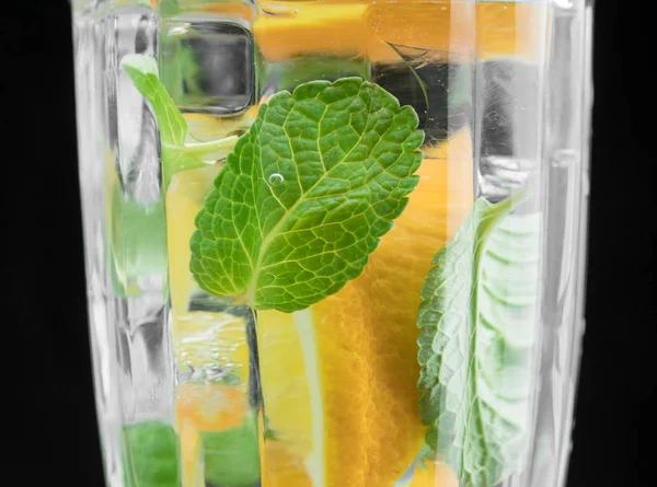 Szkło z wodą, pomarańczą i miętową. Zbliżenie koktajlu na czarnym tle. napój cytrusowy. pomarańczowy w szklance. — Zdjęcie stockowe