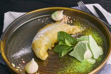 Vanilyalı dondurma ve koyu ahşap bir masa portre üzerinde beze bir kepçe ile pişmiş elma strudel. Restoran servis tatlı.