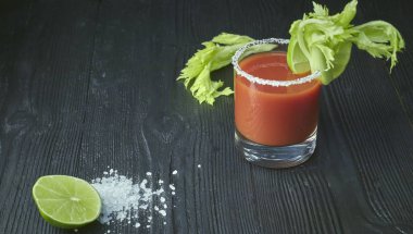 Bloody mary cockcocktail kanlı Mary ile kireç ve kereviz, tuz ve aperatifler siyah ahşap bir masa üzerinde bir cam. yatay bir cocktail.tail görünümünü