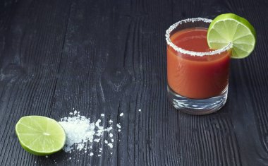 Bloody mary cockcocktail kanlı Mary ile kireç ve kereviz, tuz ve aperatifler siyah ahşap bir masa üzerinde bir cam. yatay bir cocktail.tail görünümünü