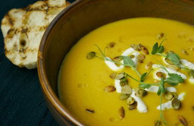 Krem ve Kabak tohumları ile bir kase kabak çorbası. Vegan çorbası. Koyu ahşap arka plan.