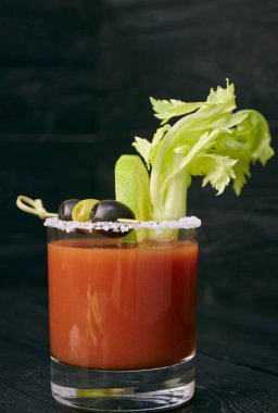 Kireç ve kereviz, tuz ve aperatifler siyah ahşap bir masa üzerinde bir cam ile kokteyl Bloody Mary. bir kokteyl dikey görünüm.