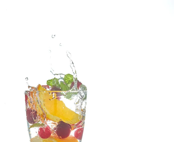 Laranja salpicando em um copo de água com hortelã e bagas em um fundo branco. refrescante bebida de verão com citrinos . — Fotografia de Stock