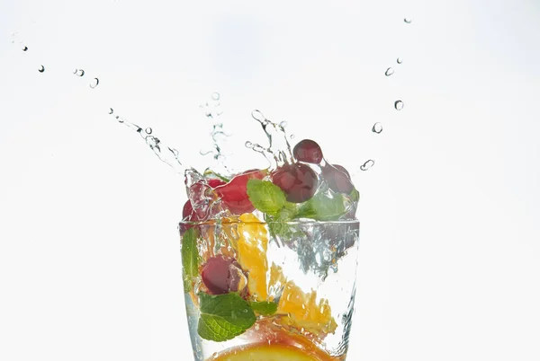 Laranja salpicando em um copo de água com hortelã e bagas em um fundo branco. refrescante bebida de verão com citrinos . — Fotografia de Stock