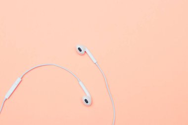 Pastel arka planda kulaklıklar. Şeftali arka planda beyaz kulaklıklar. Yukarıdan bak. Uzayın Moda Renkli Fotoğrafını Kopyala Renkli kağıt arkaplanlı minimal stil. Müzik konsepti