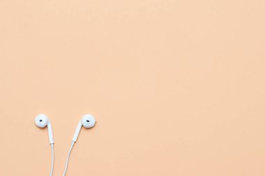 Pastel arka planda kulaklıklar. Şeftali arka planda beyaz kulaklıklar. Yukarıdan bak. Uzayın Moda Renkli Fotoğrafını Kopyala Renkli kağıt arkaplanlı minimal stil. Müzik konsepti