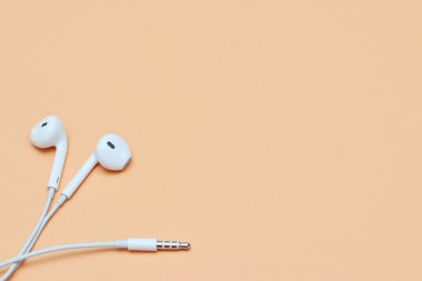 Pastel arka planda kulaklıklar. Şeftali arka planda beyaz kulaklıklar. Yukarıdan bak. Uzayın Moda Renkli Fotoğrafını Kopyala Renkli kağıt arkaplanlı minimal stil. Müzik konsepti