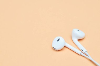 Pastel arka planda kulaklıklar. Şeftali arka planda beyaz kulaklıklar. Yukarıdan bak. Uzayın Moda Renkli Fotoğrafını Kopyala Renkli kağıt arkaplanlı minimal stil. Müzik konsepti