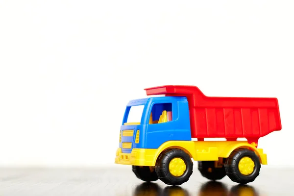 Childrens toy truck, a multi-colored plastic dump truck on a white background, copy space. toys for boys.
