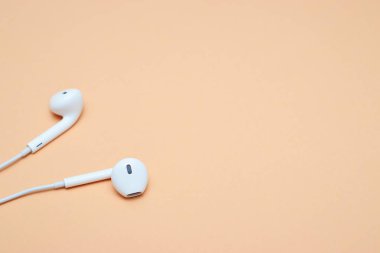 Pastel arka planda kulaklıklar. Şeftali arka planda beyaz kulaklıklar. Yukarıdan bak. Uzayın Moda Renkli Fotoğrafını Kopyala Renkli kağıt arkaplanlı minimal stil. Müzik konsepti
