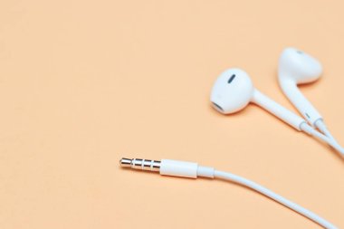 Pastel arka planda kulaklıklar. Şeftali arka planda beyaz kulaklıklar. Yukarıdan bak. Uzayın Moda Renkli Fotoğrafını Kopyala Renkli kağıt arkaplanlı minimal stil. Müzik konsepti