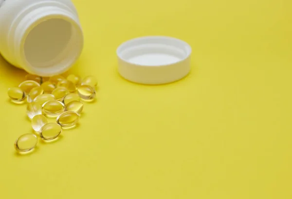 Cápsulas de medicina farmacêutica, comprimidos e cápsulas e um frasco sobre um fundo amarelo. Copiar espaço para texto. conceito de medecina e vitaminas em comprimidos . — Fotografia de Stock