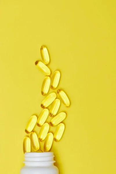 Cápsulas de medicina farmacéutica, pastillas y cápsulas y un frasco en una vista superior de fondo amarillo. Copia espacio para texto. El concepto de medicina y vitaminas en las píldoras . —  Fotos de Stock