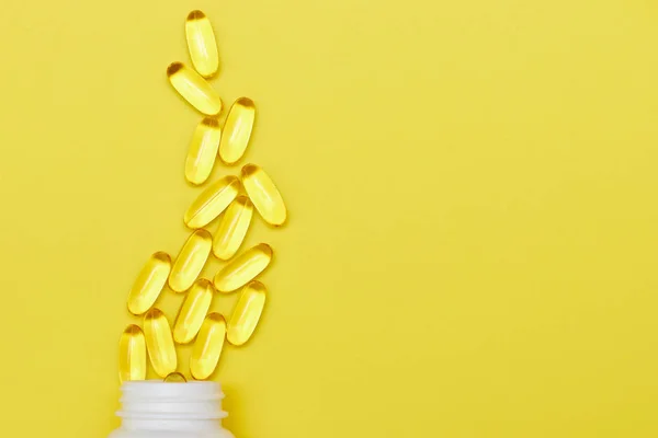 Cápsulas de medicina farmacéutica, pastillas y cápsulas y un frasco en una vista superior de fondo amarillo. Copia espacio para texto. El concepto de medicina y vitaminas en las píldoras . —  Fotos de Stock