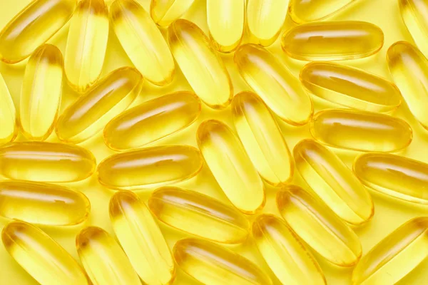 Fundo de cápsulas e medicina farmacêutica close-up, pílulas e cápsulas em um fundo amarelo vista superior. O conceito de medicina e vitaminas em comprimidos . Imagens Royalty-Free