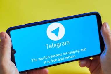 Hilversum, Hollanda - 23 Ağustos 2019 bir kız elinde sarı arka plan üzerinde Telegram Messenger uygulaması ile bir akıllı telefon. Sosyal ağlarda tarih kavramı.