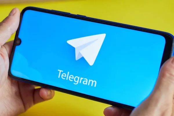 Hilversum, Hollanda - 23 Ağustos 2019 bir kız elinde sarı arka plan üzerinde Telegram Messenger uygulaması ile bir akıllı telefon. Sosyal ağlarda tarih kavramı.