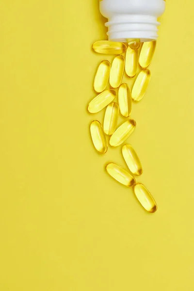 Kapseln aus der pharmazeutischen Medizin, Tabletten und Kapseln und eine Flasche auf gelbem Hintergrund von oben. Kopierraum für Text. das Konzept der Medizin und Vitamine in Pillen. — Stockfoto