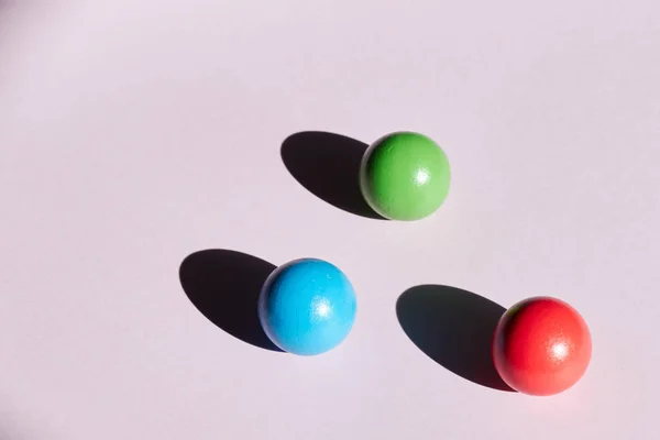 Três bolas coloridas em um fundo claro com sombras duras. fundo abstrato para design. Geometria do espaço de cópia — Fotografia de Stock
